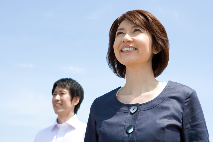 Man and woman smiling with their back against blue sea